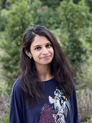Headshot of Tayeba Batool, with a navy blue shirt with flowers and birds printed
